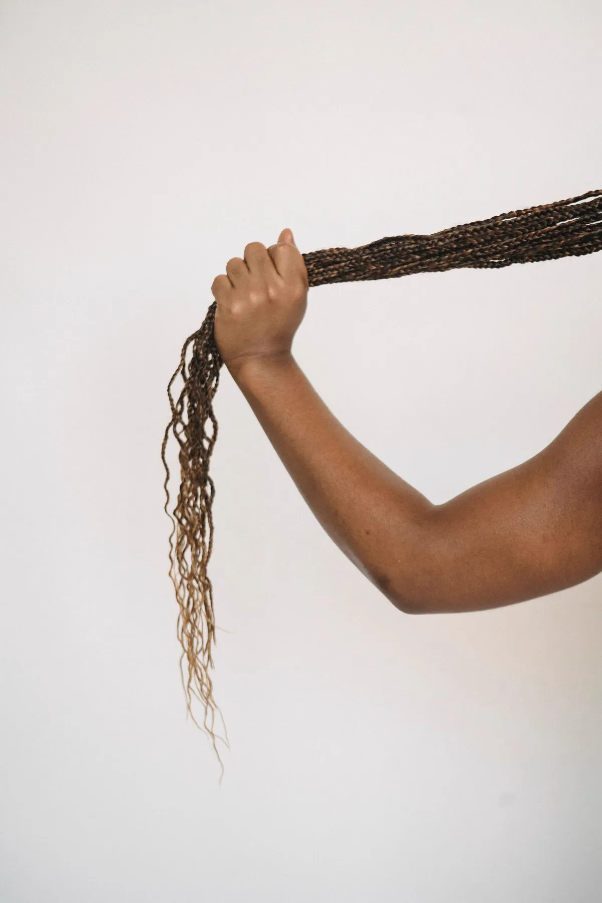 Hand holding a long ponytail of braids